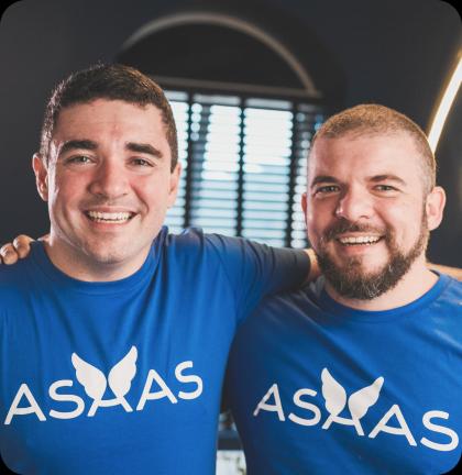 Piero e Diego, os fundadores do Asaas, abraçados e sorrindo. Ambos estão vestindo a camiseta com o logotipo da empresa.